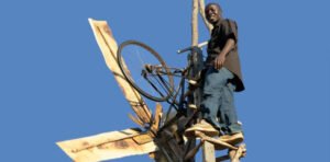 William Kamkwamba di samping kincir angin pertama yang ia bangun dari barang bekas di Malawi.