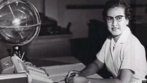 Katherine Johnson tersenyum sambil memegang buku