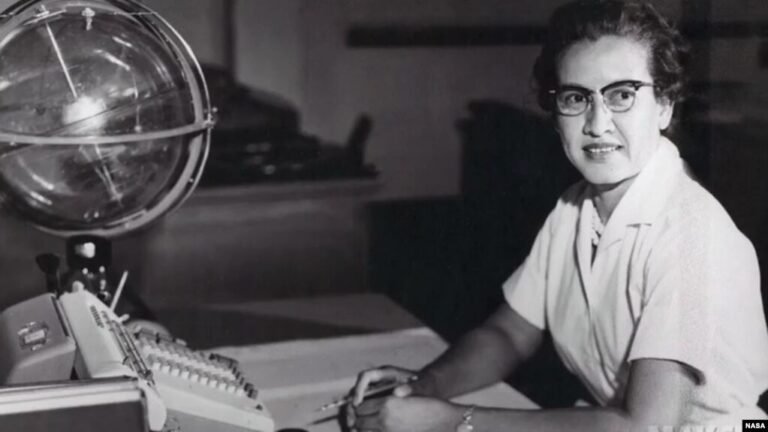 Katherine Johnson tersenyum sambil memegang buku